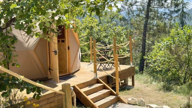 Une terrasse en bois menant à une structure en forme de dôme géodésique, protégée par une barrière en corde.