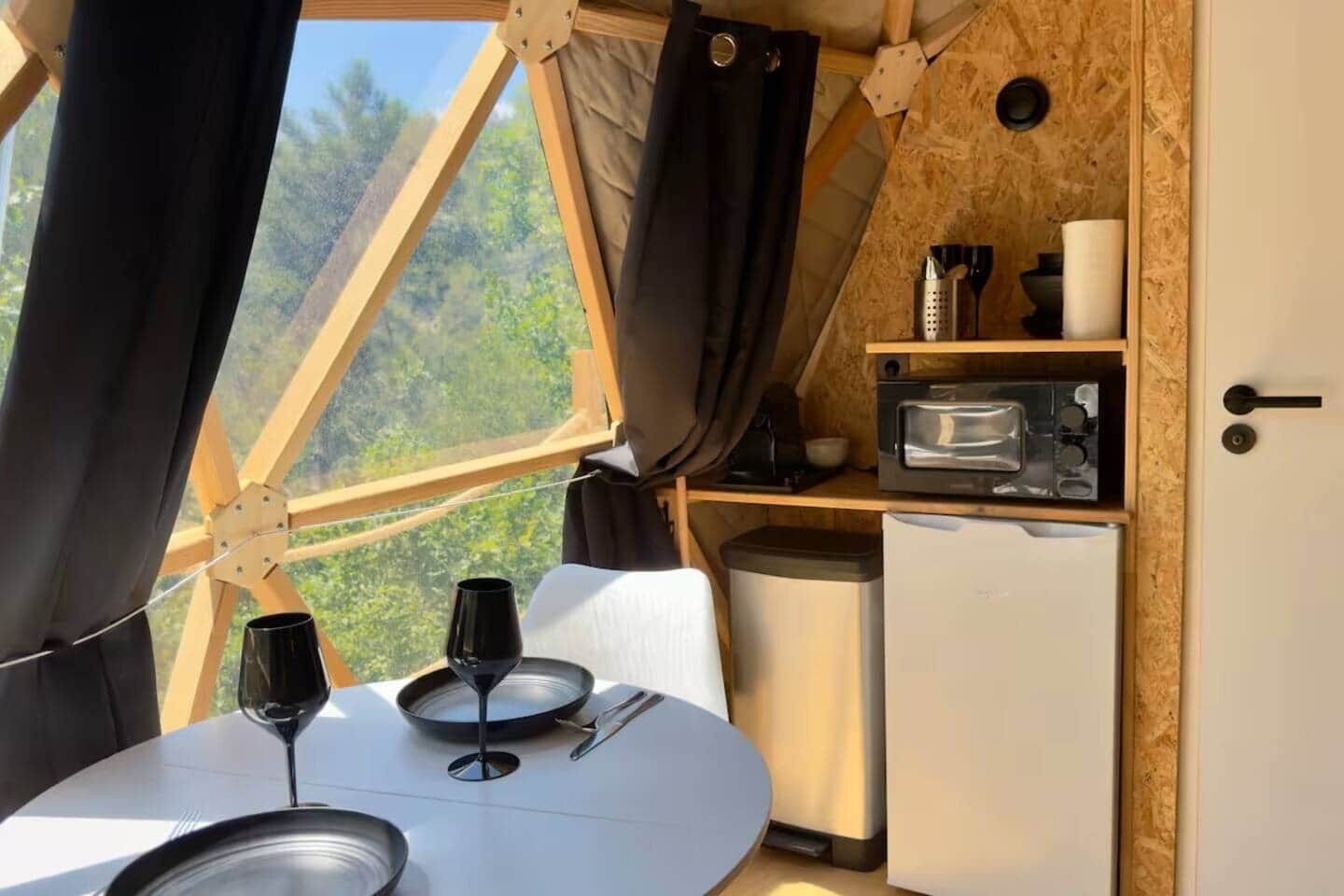 Un coin repas accueillant avec une table dressée pour deux personnes, un four à micro-ondes et une poubelle.