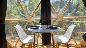 Un coin repas avec une table ronde, deux chaises et un verre à vin.