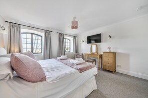 A hotel room with a bed, a desk, a chair, a television, and a window with curtains. - 6 The Granary - sleeps 2 guests  in 1 bedroom (Wells-next-the-Sea)