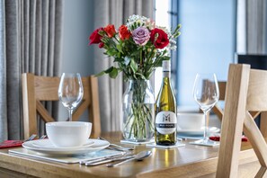 A dining table set with a white bowl, wine glasses, cutlery, and a bottle of wine. - 6 The Granary - sleeps 2 guests  in 1 bedroom (Wells-next-the-Sea)