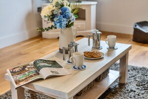 A wooden table with a magazine, a coffee pot, a cup, and a plate of cookies. - Curlew Cottage - sleeps 6 guests  in 3 bedrooms (Brancaster)