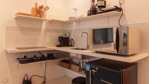 Et moderne køkken med hvide skabe, et sort køleskab, en mikrobølgeovn og en kaffemaskine.