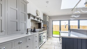 A modern kitchen with grey cabinetry, a built-in oven, and a large island with a sink. - Olive's Cottage - sleeps 6 guests  in 3 bedrooms (Burnham Market)