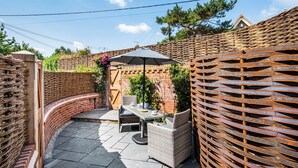 Un'area patio con mobili in rattan, un tavolo e un ombrellone.