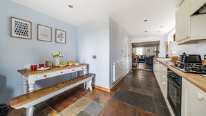 A modern kitchen with a wooden bench, white cabinetry, and a tiled floor. - Longview Cottage - sleeps 6 guests  in 3 bedrooms (Wells-next-the-Sea)