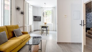 Ein modernes Wohnzimmer mit einem gelben Sofa, einem Marmortisch und einem Essbereich mit Tisch und Stühlen.