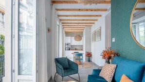 Ein modernes Wohnzimmer mit einem blauen Sofa, einer türkis farbenen Akzentwand und einer Küche im Hintergrund.