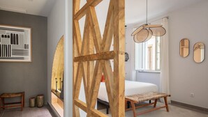 Une chambre à coucher moderne avec un lit, une cloison en bois, un luminaire suspendu et une œuvre d’art abstraite encadrée accrochée au mur.