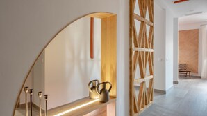 Un intérieur moderne avec un mur incurvé, un lambris en bois et un banc agrémenté de vases décoratifs.