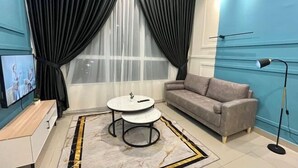 Un salon moderne avec un canapé, une petite table ronde, un téléviseur et une lampe sur pied.