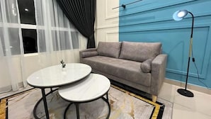 Un salon moderne avec un canapé gris, une table basse ronde en verre et un lampadaire.