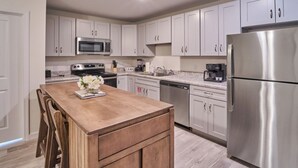 A modern kitchen with white cabinets, stainless steel appliances, and a wooden island. - Ruby 212: 1BD | Great LOCATION + Shared Amenities! (Pigeon Forge)