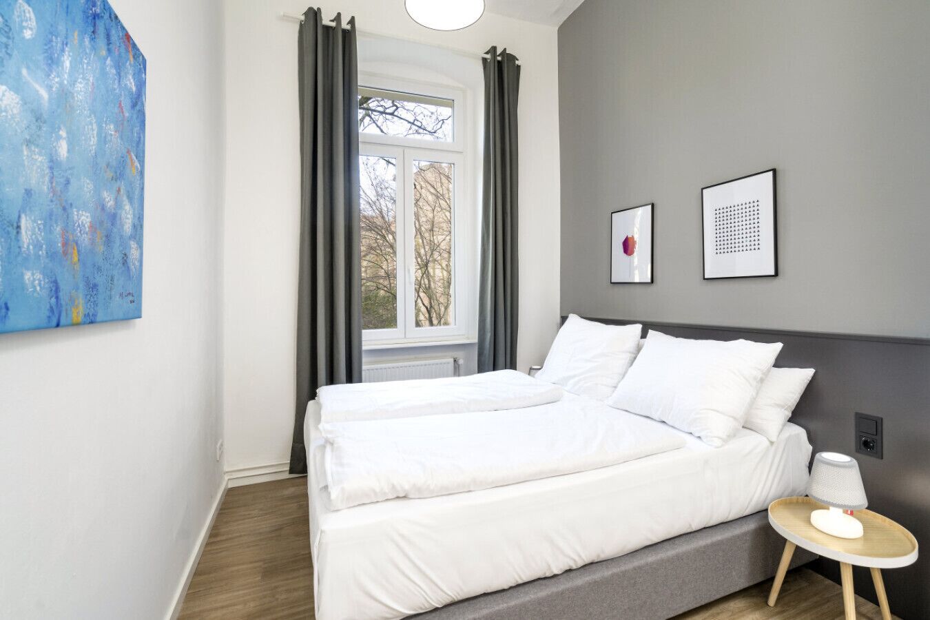 A modern bedroom with a bed, a bedside table, and a window with curtains.