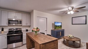 A modern kitchen with stainless steel appliances, a wooden island, and a ceiling fan. - Ruby 213: 1BD | Great LOCATION + Shared Amenities! (Pigeon Forge)