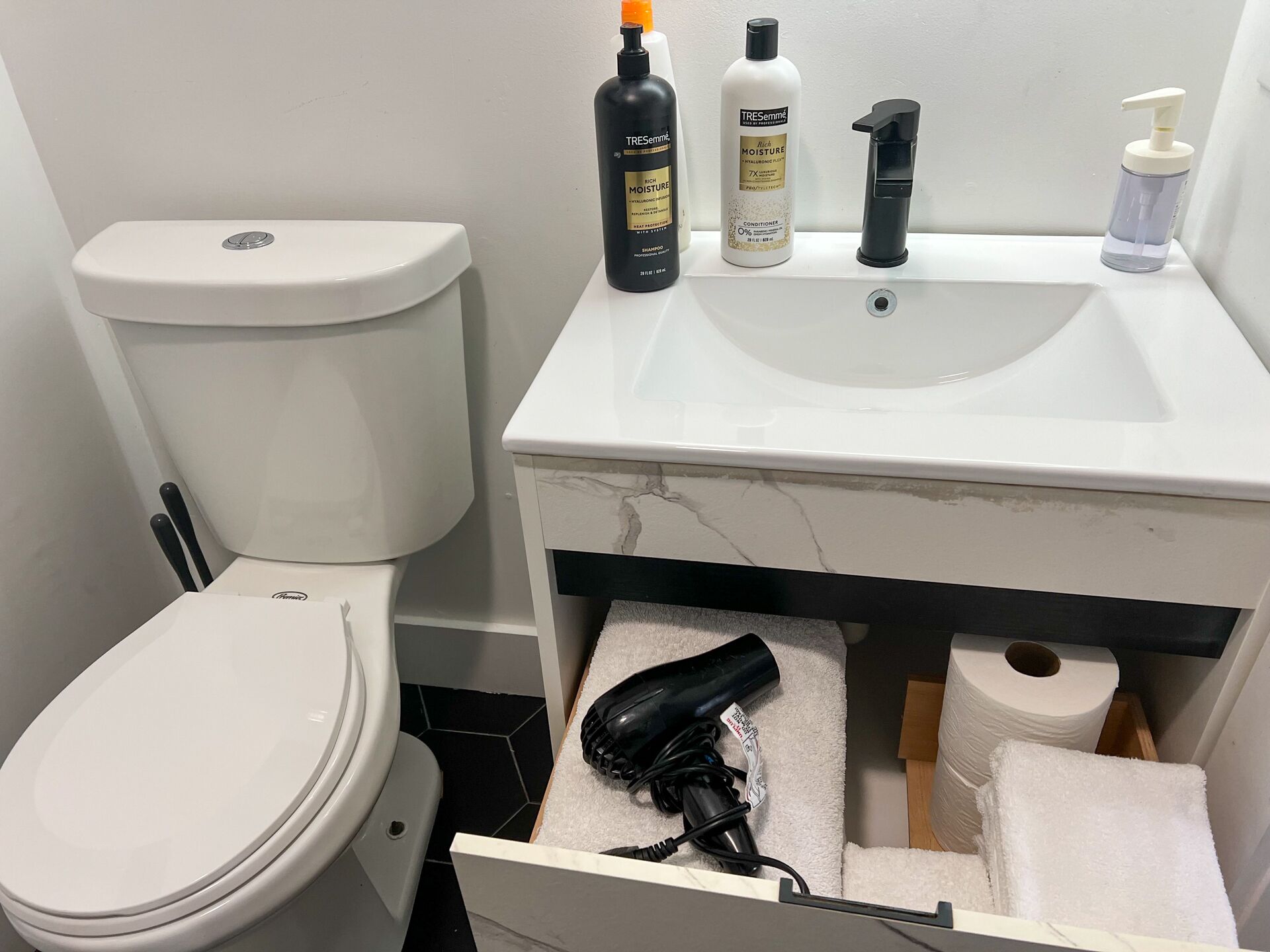 Un baño con inodoro, lavamanos y toallero.