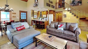 A spacious living area with a sofa, a coffee table with a chess set, and a staircase leading to an upper level. - River's Edge Retreat (Sevierville)