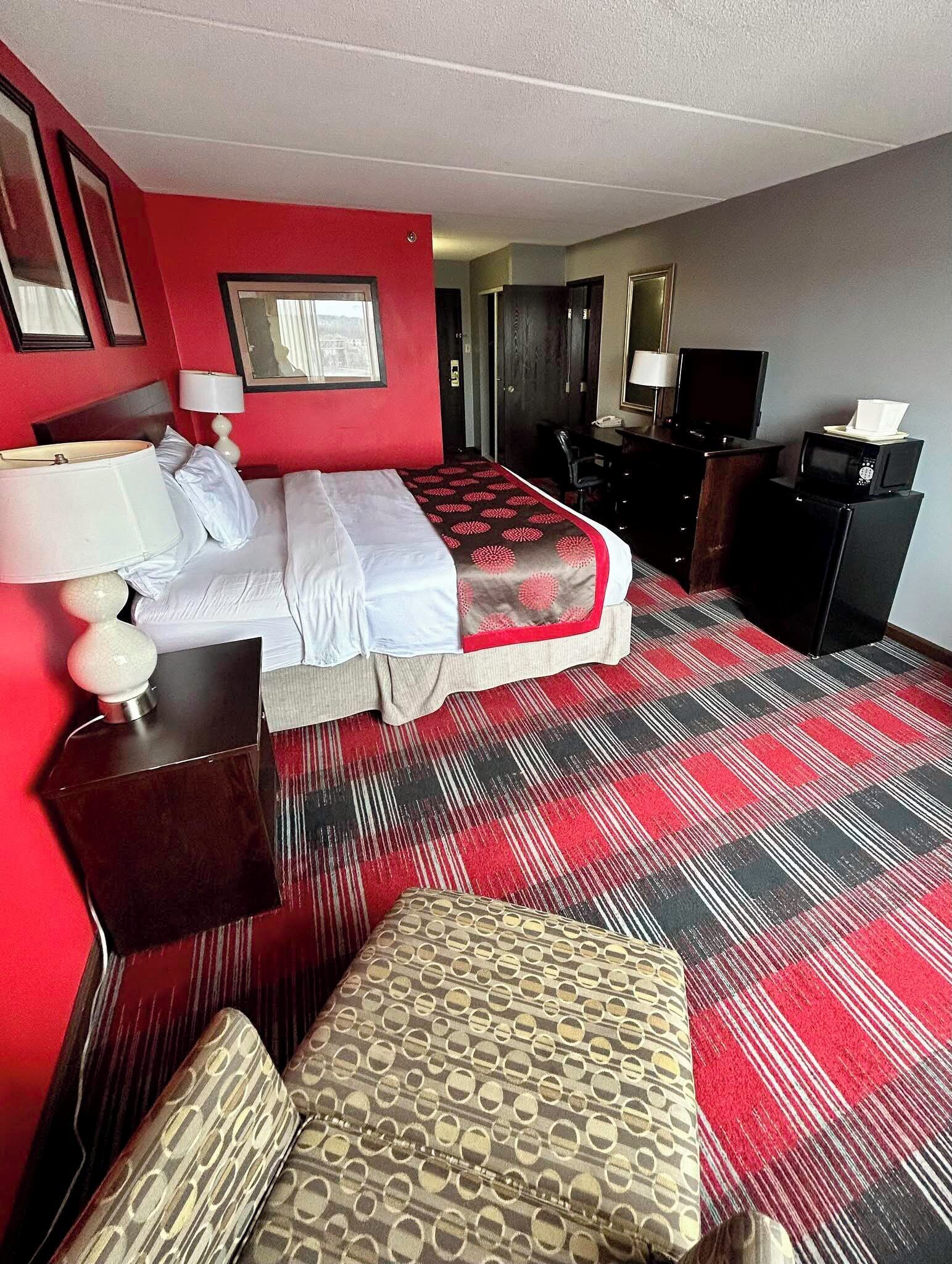 Een hotelkamer met een bed, een bureau met een computer, een stoel en een televisie.