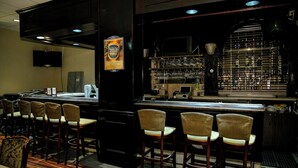 A bar area with a counter, bar stools, and a wall-mounted television. - Cozy Albany room with breakfast (Albany)