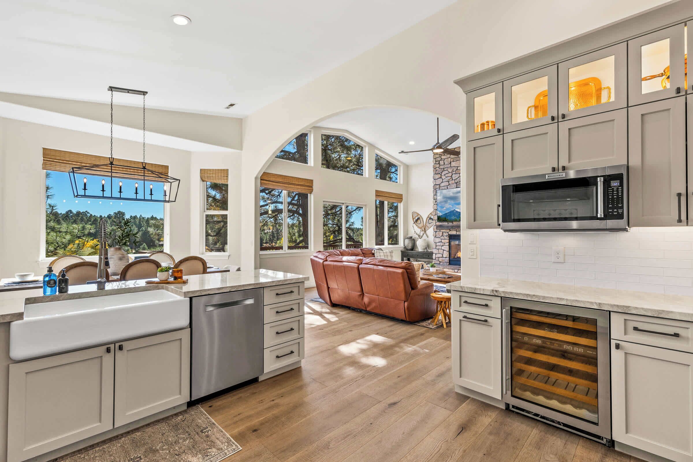 A modern kitchen with a built-in oven, a microwave, and a wine cooler. There is a large island with a sink and a seating area with a leather sofa.