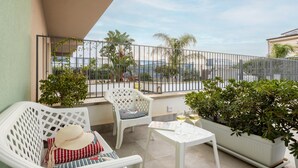 A balcony with white furniture, a table with a glass of wine, and a view of the sea. - Holiday Home 'Calarossa Tourist House Di Ale & Anny' with Sea View, Wi-Fi, and Air Conditioning (terrasini)