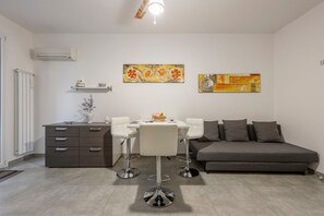 Een moderne woonkamer met een bank, een eettafel met stoelen, een kast en twee wanddecoraties.