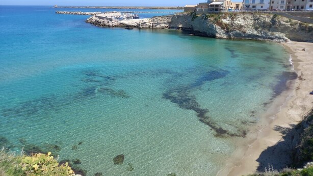A coastal area with clear waters, rocky formations, and buildings on the shore. - Holiday Home 'Calarossa Tourist House Di Ale & Anny' with Sea View, Wi-Fi, and Air Conditioning (terrasini)