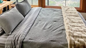 Ein Schlafzimmer mit einem großen Bett, zwei Fenstern und Blick auf die Landschaft.