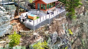 Eine Holzhütte mit Steinunterbau, einer Terrasse und einem Whirlpool.