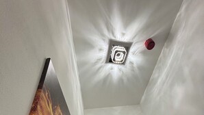 Passadís estret amb una làmpada al sostre i un quadre penjat a la paret.