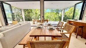 Un espace repas moderne avec une table en bois dressée pour quatre personnes, entourée de chaises en osier.