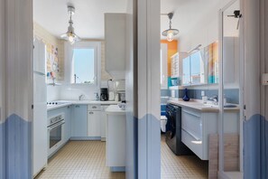 Een keuken met een centraal eiland, een kookplaat, een spoelbak en een vaatwasser.