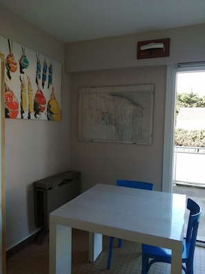 Um quarto com uma mesa branca, cadeiras azuis, um mapa na parede e um quadro.