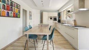 Una cucina moderna con isola centrale, mobili bianchi e zona pranzo con sedie blu.