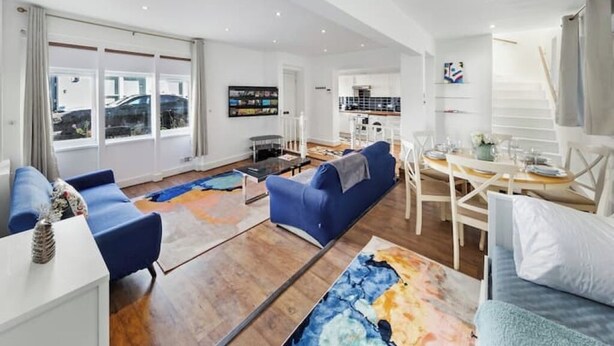 A modern living room with a blue sofa set, a coffee table, and a large abstract rug. - Modern Spacious 2 Bedroom House in Central London (Kensington )