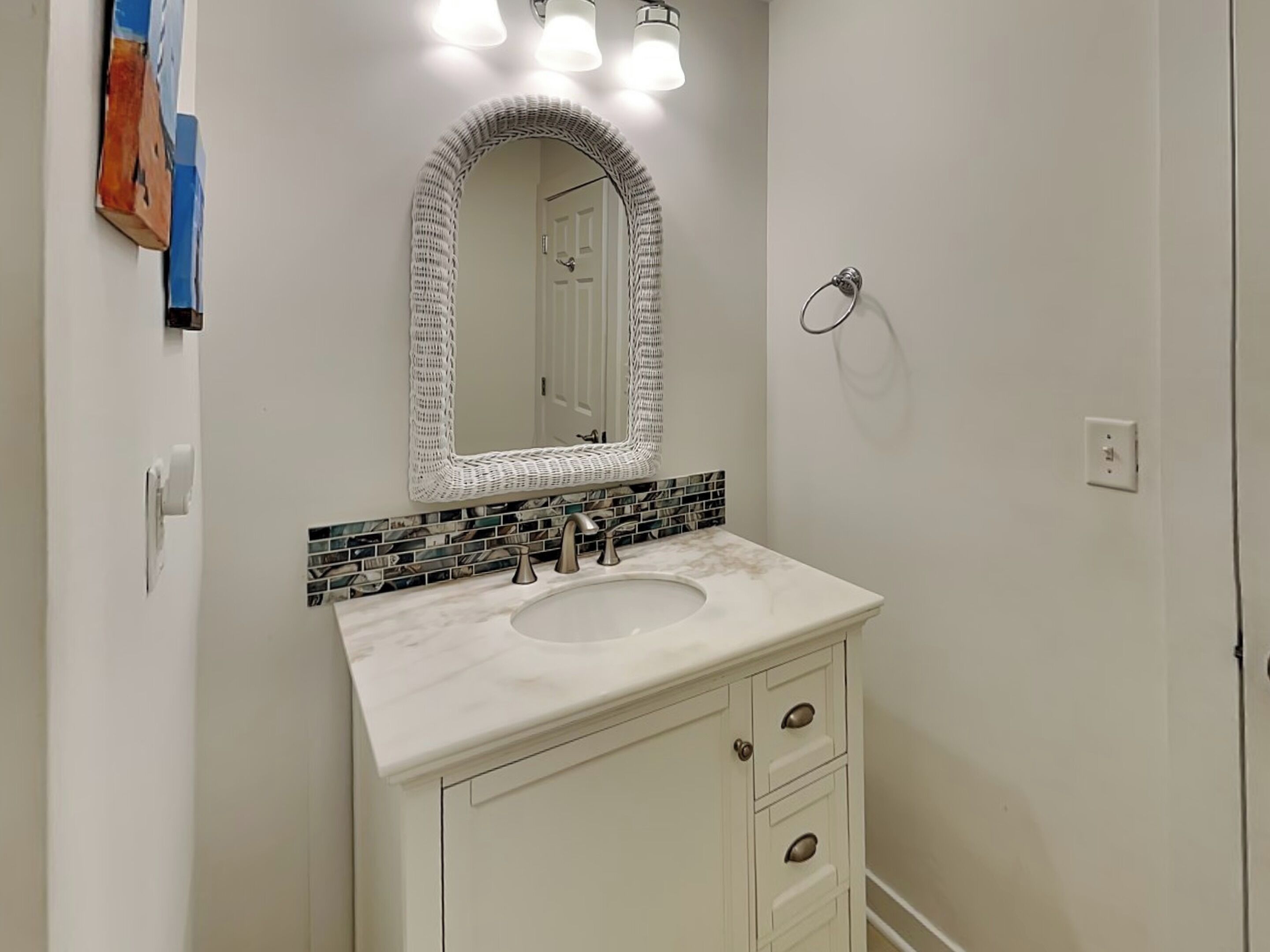 A bathroom with a white vanity, a sink, and a mirror with a mosaic backsplash.