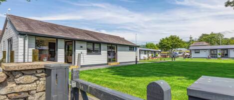 A row of single-story buildings with a stone wall and a wooden fence in the foreground.