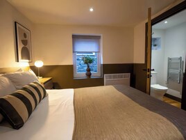 A hotel room with a bed, bedside lamp, window with a view, and a bathroom with a towel rack.
