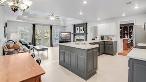 Una cocina amplia con una isla central, muebles oscuros y un comedor con mesa y sillas de madera.