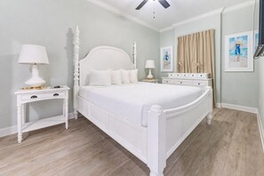 Quarto bem arrumado com uma cama grande, mesas de cabeceira e um ventilador de teto.