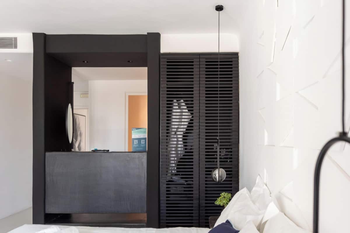 Une chambre moderne avec un grand lit, une armoire intégrée et une salle de bain ouverte.