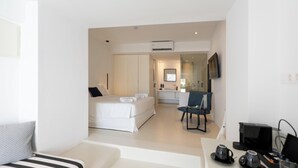 Une chambre d’hôtel moderne équipée d’un lit, d’un bureau avec un ordinateur, d’une chaise et d’un téléviseur.