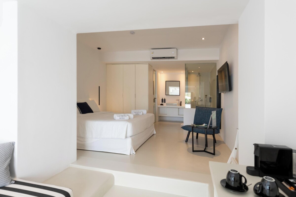 Une chambre d’hôtel moderne équipée d’un lit, d’un bureau avec un ordinateur, d’une chaise et d’un téléviseur.
