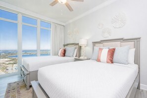 Ein Schlafzimmer mit zwei Betten, einem großen Fenster mit Blick, einem Deckenventilator und Wanddekoration.