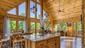 A spacious wooden cabin with large windows, a kitchen with granite countertops, and a cozy living area. - Ridge Hollow Retreat – Hot Tub, Fire Pit, Dogs (Gatlinburg)