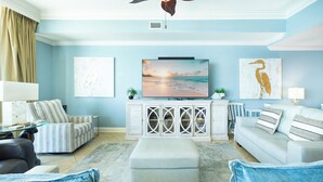 Ein Wohnzimmer mit Fernseher, Sitzgelegenheiten und Kunstwerken an den Wänden.
