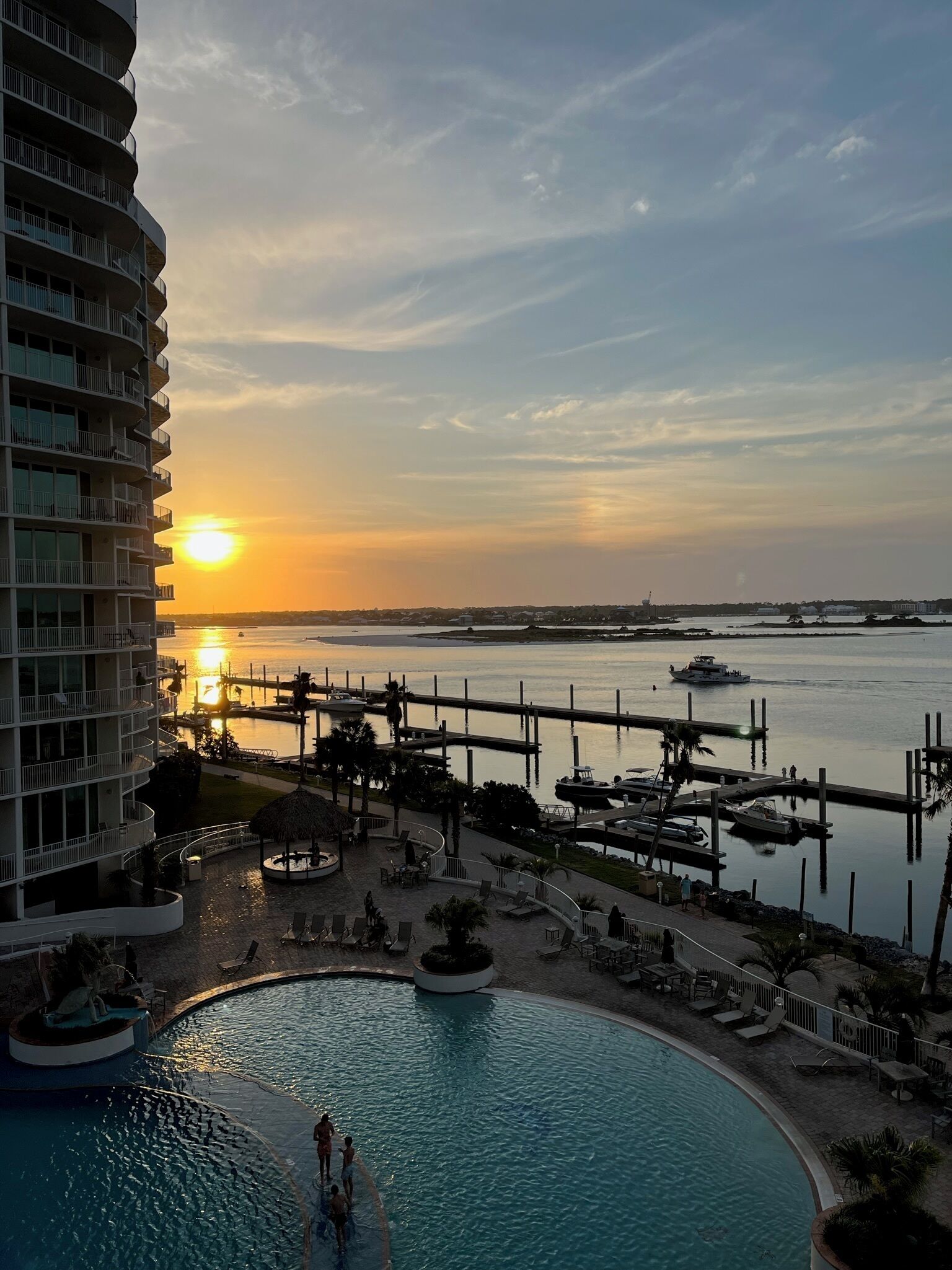 A resort with a swimming pool, a marina, and a sunset view.