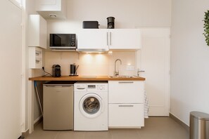 Eine kleine Küche mit Waschmaschine, Mikrowelle und Kaffeemaschine.