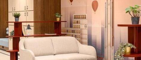 Una sala de estar moderna con sofá, reposapiés y estanterías, con un tapete de diseño geométrico y un mural con vista a la ciudad.
