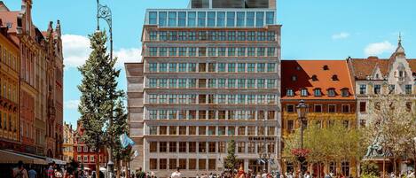 A modern building with a glass facade, surrounded by historic architecture.